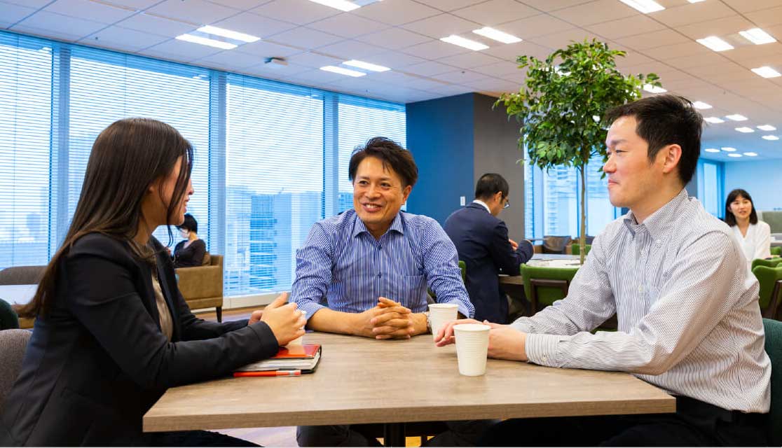 コミュニケーションスペースでテーブルを囲んで会話をする社員